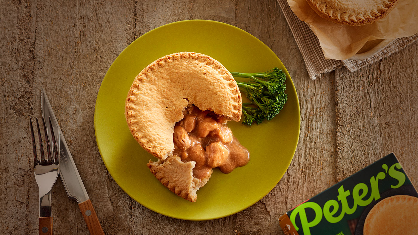 Peter's chicken pie on a plate next to the packaging and a knife and fork